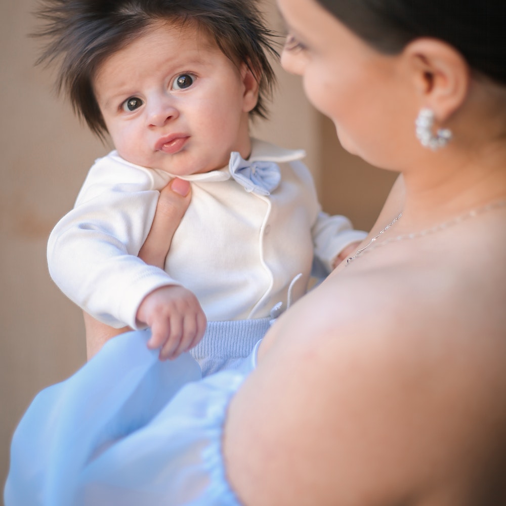 cute baby with long hair being held by mother